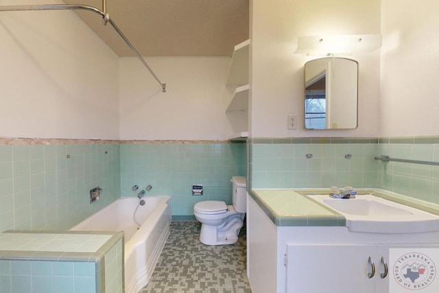 bathroom featuring vanity, toilet, a tub, and tile walls