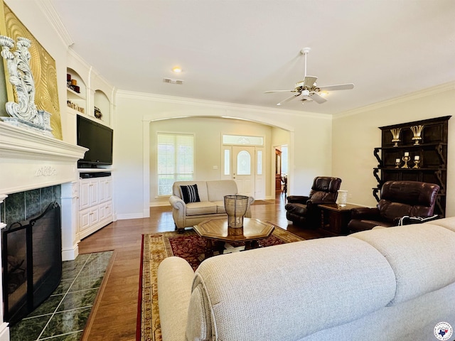 80 Tommy Hines Ln, Texarkana, TX 75501 - living room featuring a tile fireplace, dark wood finished floors, ceiling fan, arched walkways, and ornamental molding