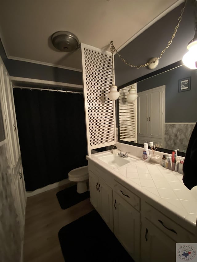 bathroom with wood-type flooring, crown molding, toilet, and vanity