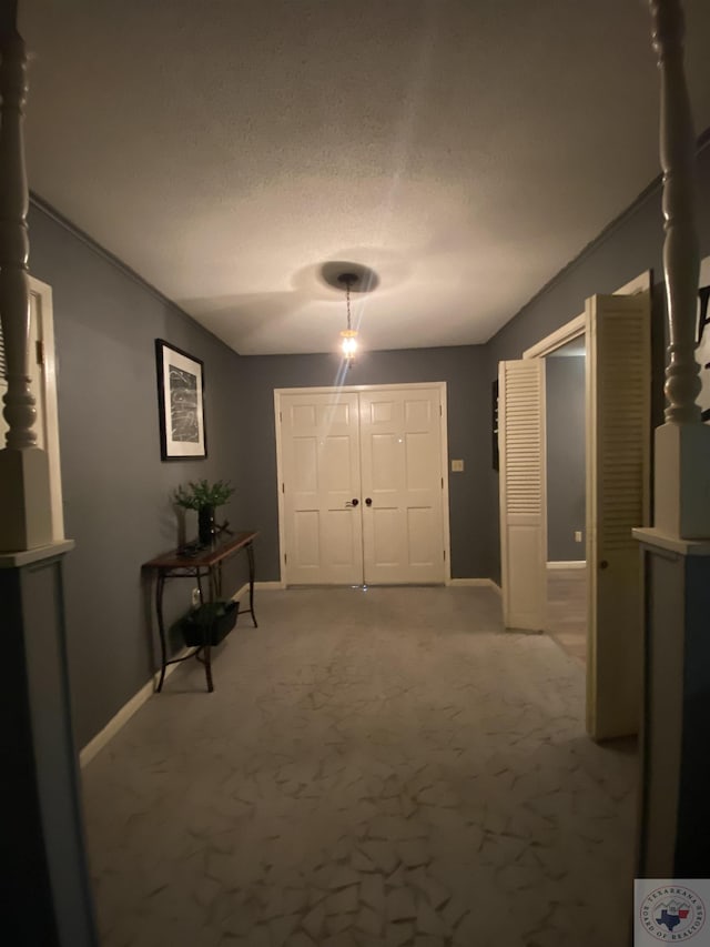 carpeted foyer entrance with a textured ceiling