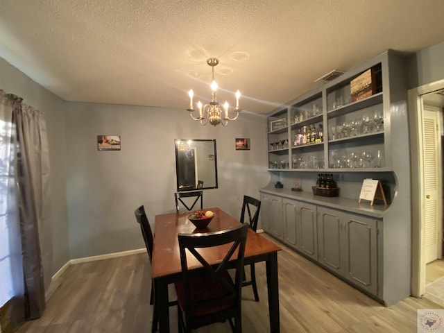 dining area featuring a chandelier, light hardwood / wood-style floors, and a textured ceiling