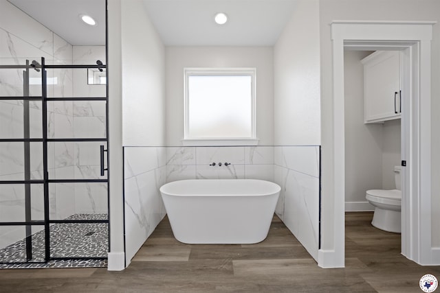 8405 Mandarin Cv, Texarkana, TX 75503 - full bathroom with tile walls, a shower stall, toilet, a freestanding bath, and wood finished floors