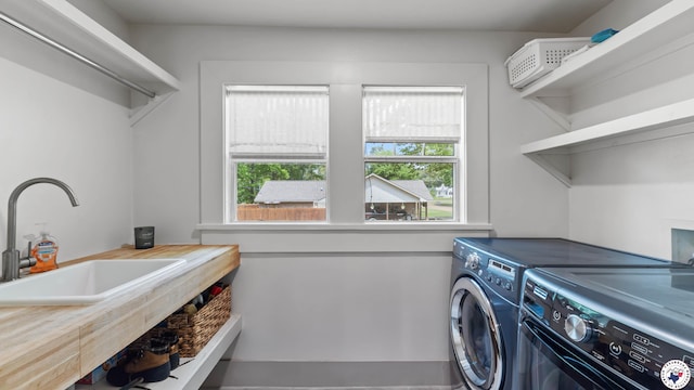 washroom with laundry area, separate washer and dryer, and a sink