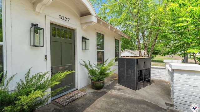 property entrance with stucco siding, central AC unit, and a patio area
