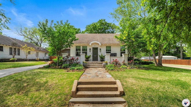 bungalow-style house with stucco siding, fence, and a front yard