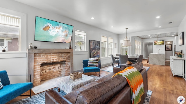 living area with a fireplace, light wood-type flooring, visible vents, and recessed lighting