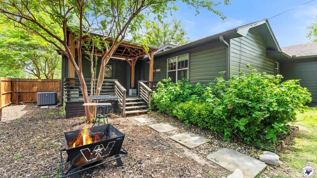view of front facade with central AC unit, fence, and an outdoor fire pit