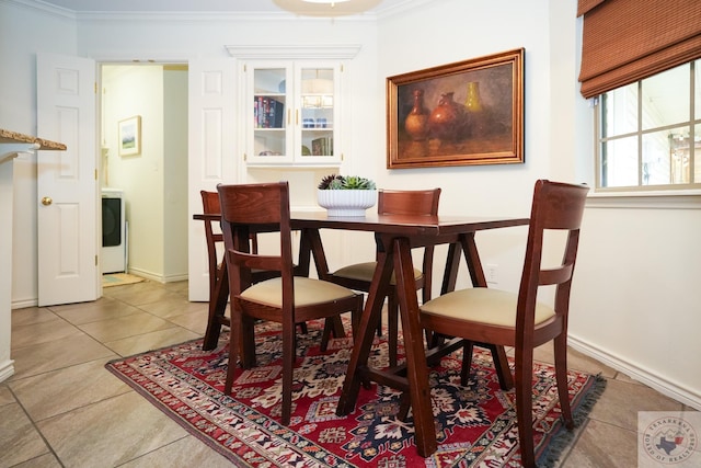 tiled dining room with ornamental molding and washer / dryer