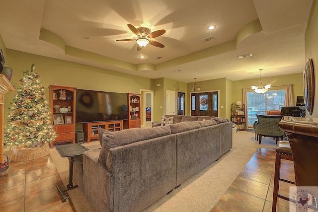 tiled living room featuring ceiling fan with notable chandelier and a raised ceiling