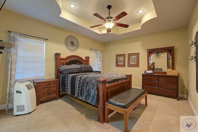 carpeted bedroom with ceiling fan and a tray ceiling