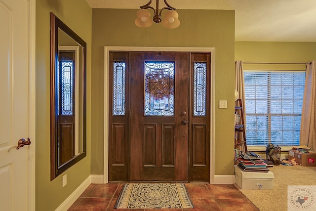 entryway featuring dark tile patterned flooring, a healthy amount of sunlight, and a notable chandelier