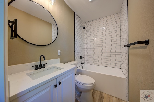 full bathroom with hardwood / wood-style flooring, tiled shower / bath combo, vanity, and toilet