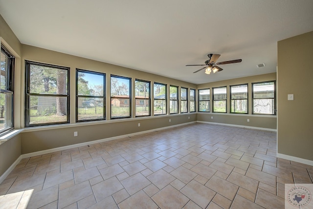 empty room with ceiling fan, a wealth of natural light, and light tile patterned floors