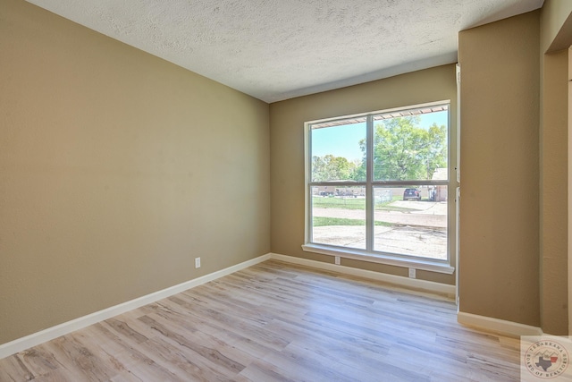 unfurnished room with light hardwood / wood-style floors and a textured ceiling