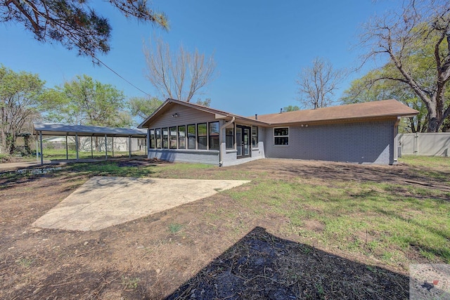 back of property with a carport, a lawn, and a sunroom