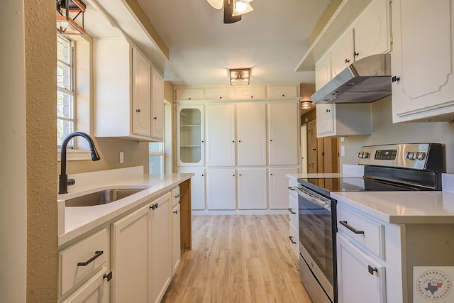 kitchen featuring white cabinetry, stainless steel range with electric stovetop, light wood-type flooring, sink, and ceiling fan