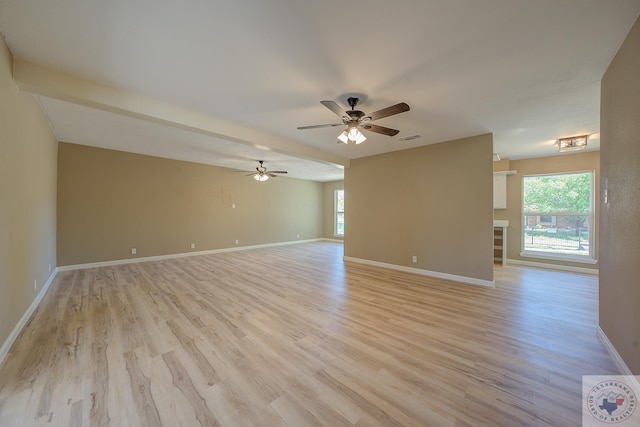 empty room with ceiling fan, a wealth of natural light, and light hardwood / wood-style flooring