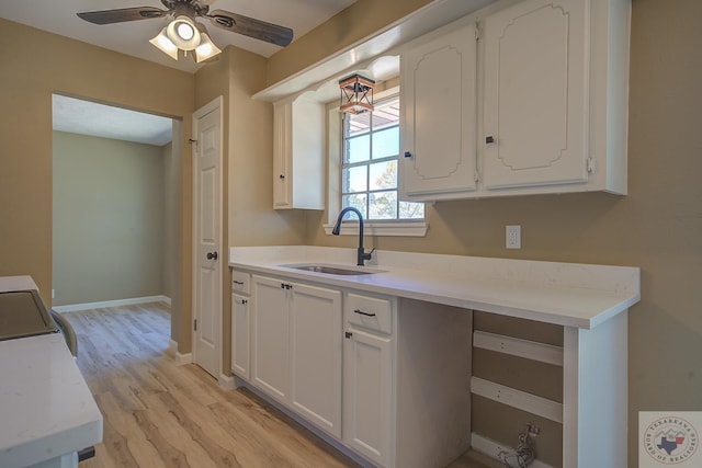 kitchen with sink, ceiling fan, white cabinetry, and light hardwood / wood-style flooring