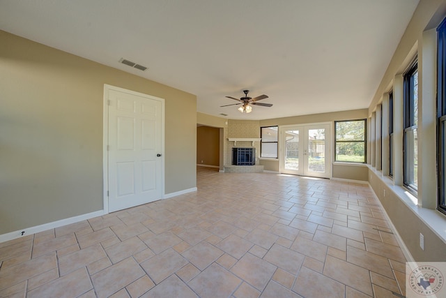 unfurnished living room featuring ceiling fan, french doors, light tile patterned floors, and a fireplace