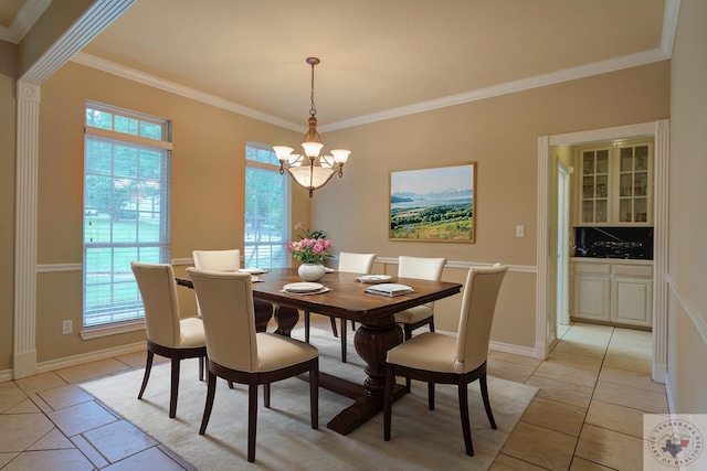 dining space with light tile patterned floors, ornamental molding, a chandelier, and a healthy amount of sunlight