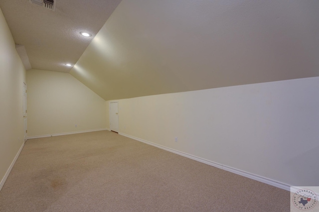 additional living space with light colored carpet, a textured ceiling, and lofted ceiling