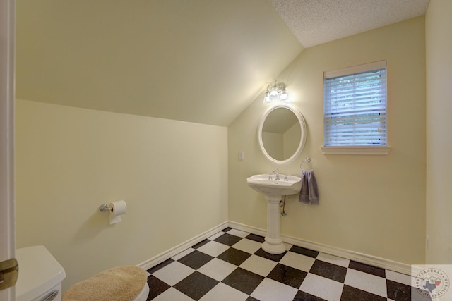 bathroom featuring a textured ceiling and vaulted ceiling