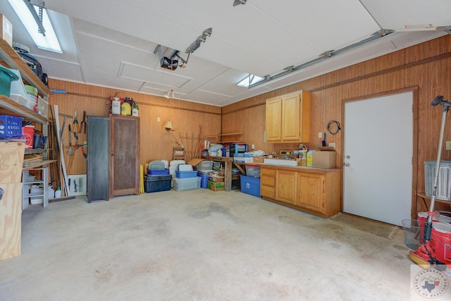 garage with wood walls, a garage door opener, and a workshop area