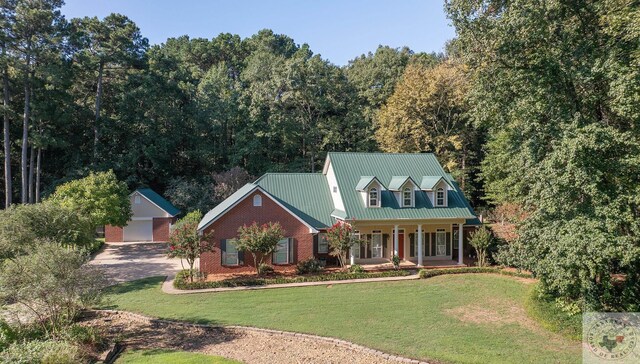 cape cod home featuring a garage, a front lawn, a porch, and an outbuilding