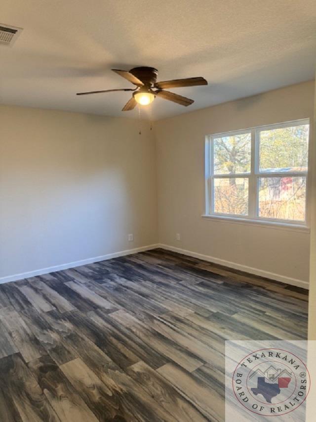 empty room with ceiling fan, a textured ceiling, and dark hardwood / wood-style flooring