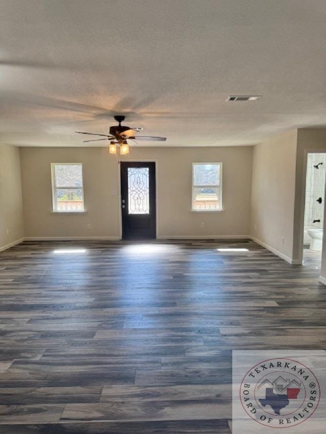 interior space with ceiling fan, a textured ceiling, and dark hardwood / wood-style floors