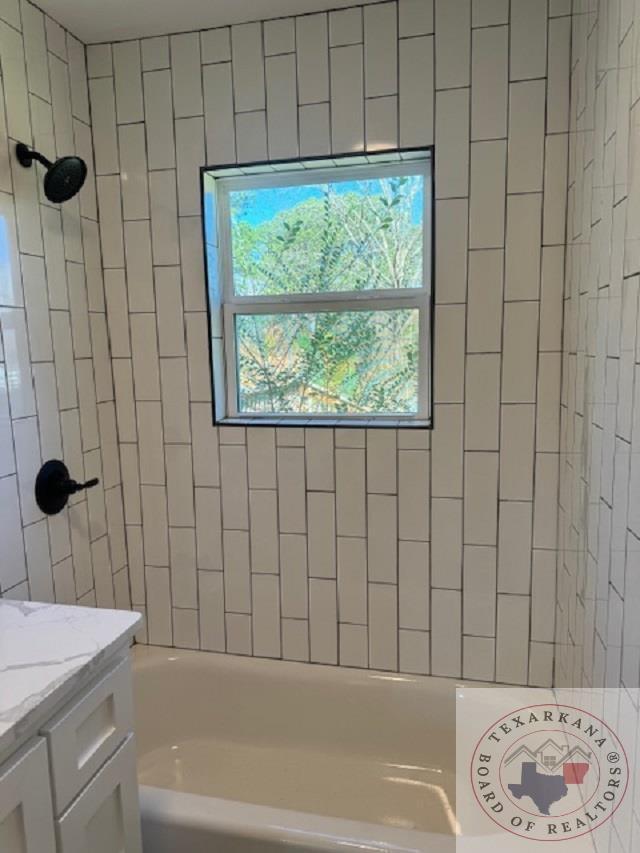 bathroom with tiled shower / bath and vanity