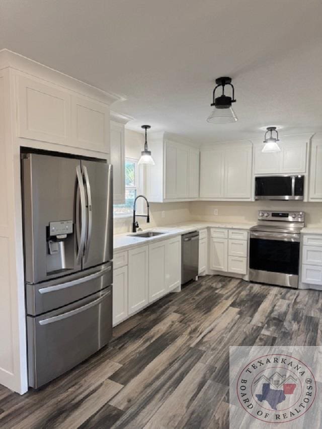 kitchen with sink, white cabinets, appliances with stainless steel finishes, and hanging light fixtures