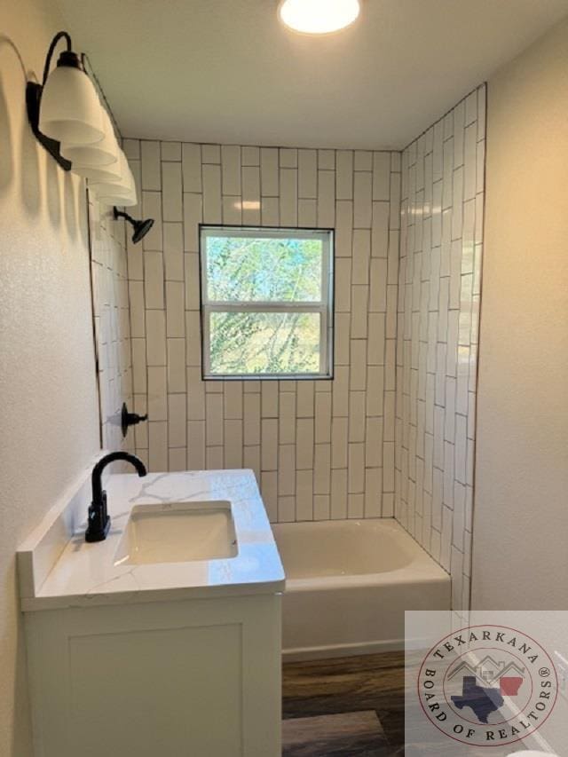 bathroom with tiled shower / bath combo, wood-type flooring, and vanity