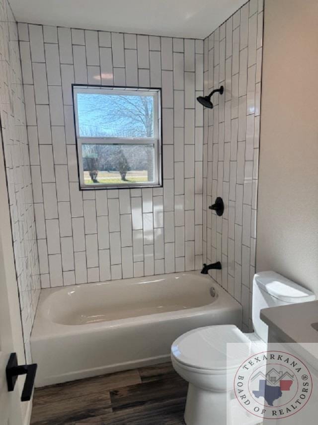 bathroom with wood-type flooring, tiled shower / bath combo, and toilet