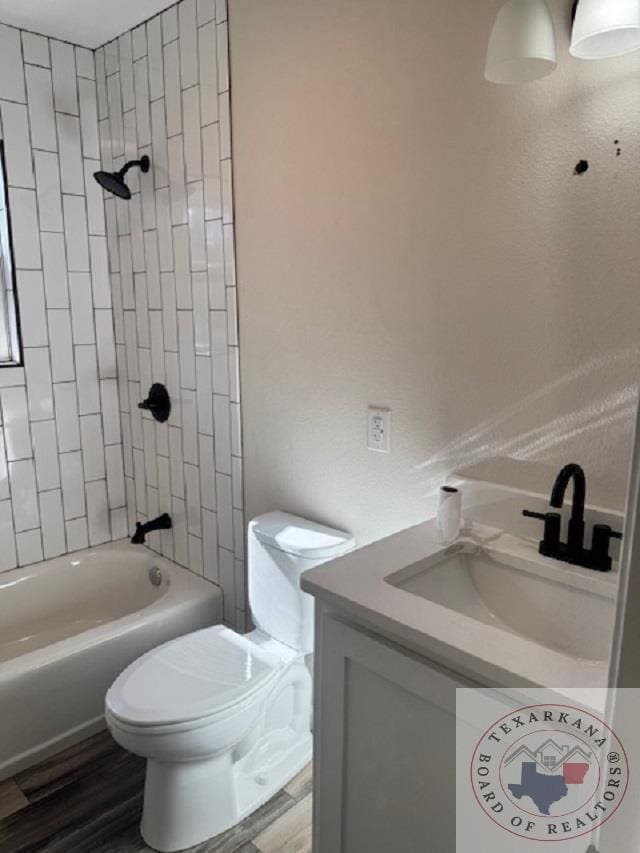 full bathroom with hardwood / wood-style flooring, toilet, vanity, and tiled shower / bath