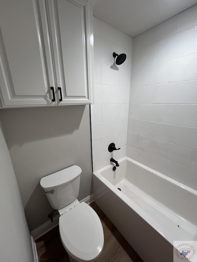 bathroom with hardwood / wood-style floors, toilet, and tiled shower / bath