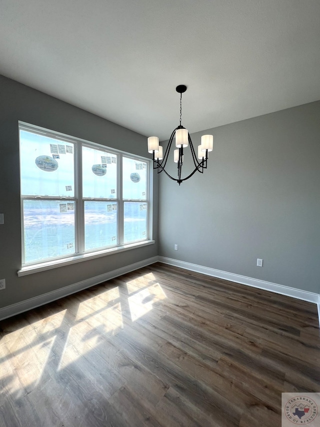 unfurnished dining area featuring a chandelier and dark hardwood / wood-style flooring