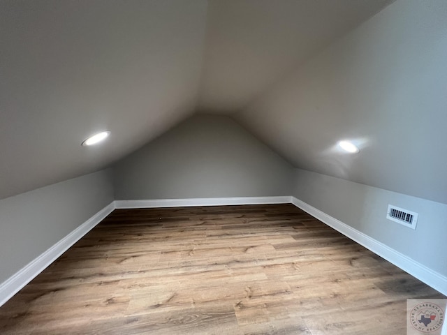 additional living space with light hardwood / wood-style floors and lofted ceiling