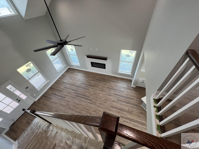 unfurnished living room with ceiling fan, a high ceiling, and hardwood / wood-style floors