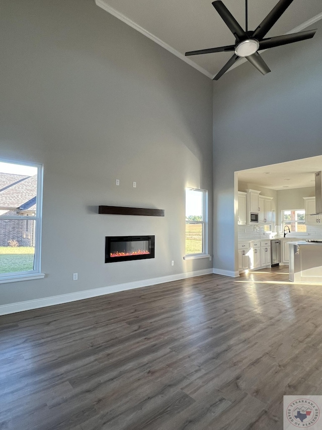 unfurnished living room featuring a high ceiling, crown molding, and dark hardwood / wood-style flooring