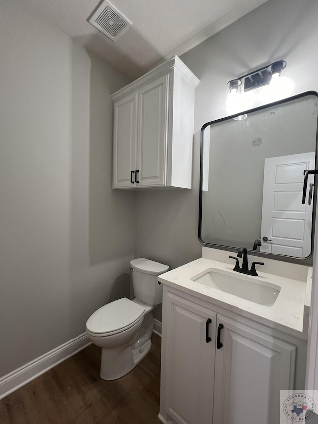 bathroom with hardwood / wood-style floors, toilet, and vanity