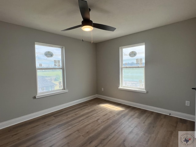 unfurnished room featuring ceiling fan, a wealth of natural light, and dark hardwood / wood-style flooring