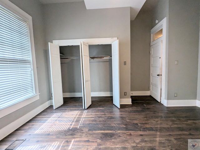 unfurnished bedroom featuring multiple closets, dark hardwood / wood-style floors, and multiple windows