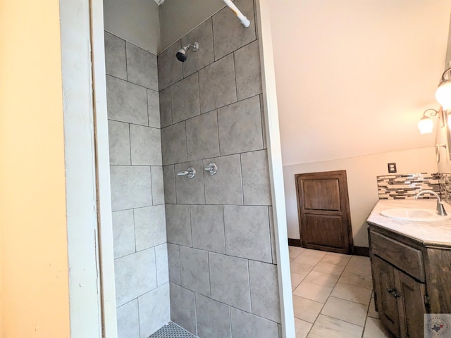 bathroom featuring tiled shower, vanity, and tasteful backsplash