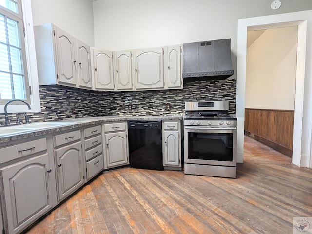 kitchen featuring wall chimney exhaust hood, sink, gray cabinetry, black dishwasher, and gas stove