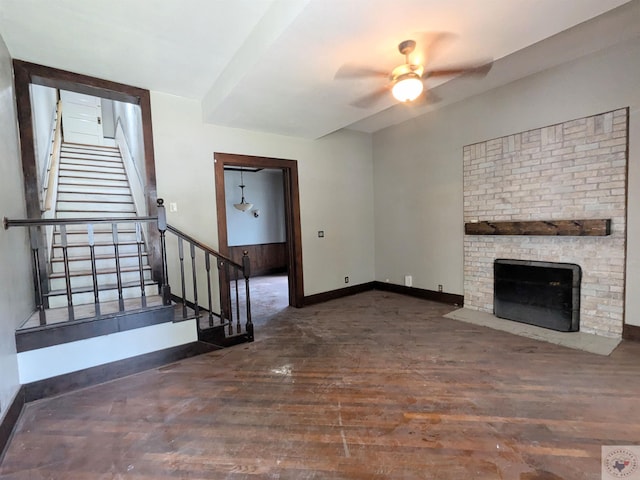 unfurnished living room featuring ceiling fan, a brick fireplace, and dark wood-type flooring