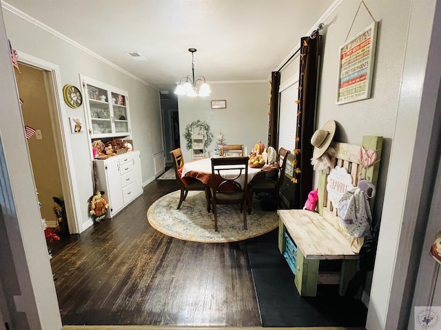 dining space featuring dark wood-type flooring, a notable chandelier, and ornamental molding