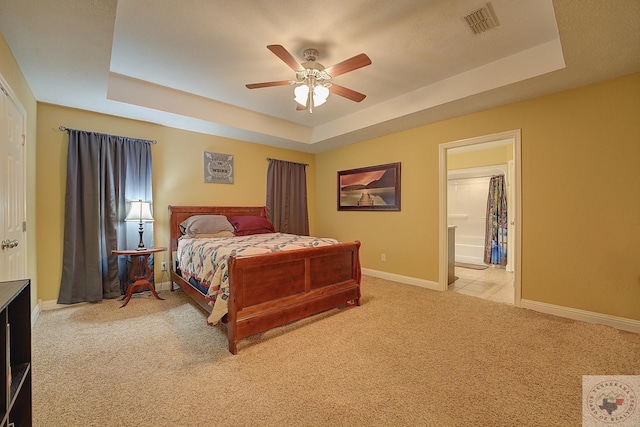 bedroom with ceiling fan, light colored carpet, and a raised ceiling