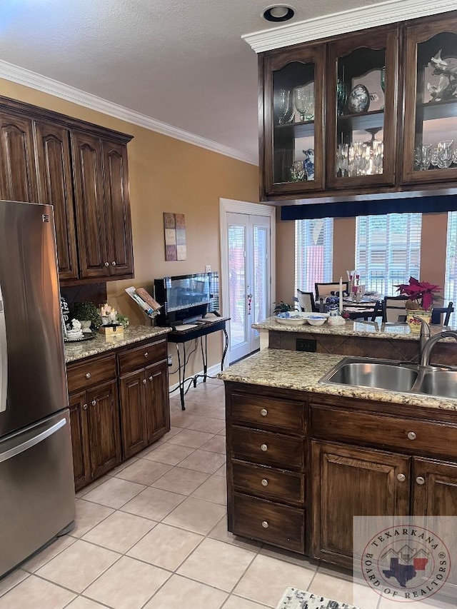 kitchen with sink, dark brown cabinets, stainless steel fridge, light tile patterned floors, and crown molding