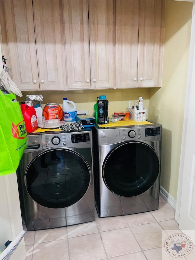 clothes washing area featuring washing machine and dryer, cabinets, and light tile patterned flooring